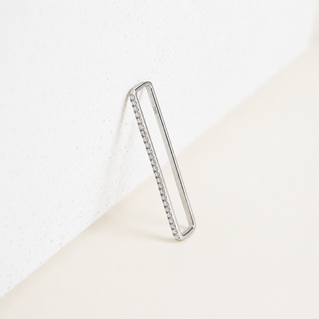 Silver hoop earring with embedded stones on a white background